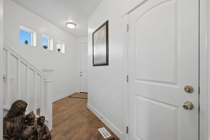 White paneled door with an arched top, wood-finish flooring, and multiple high-set windows