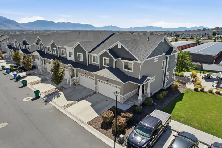Contemporary townhome featuring a two-car garage, stone and siding exterior, front landscaping, and a paved driveway
