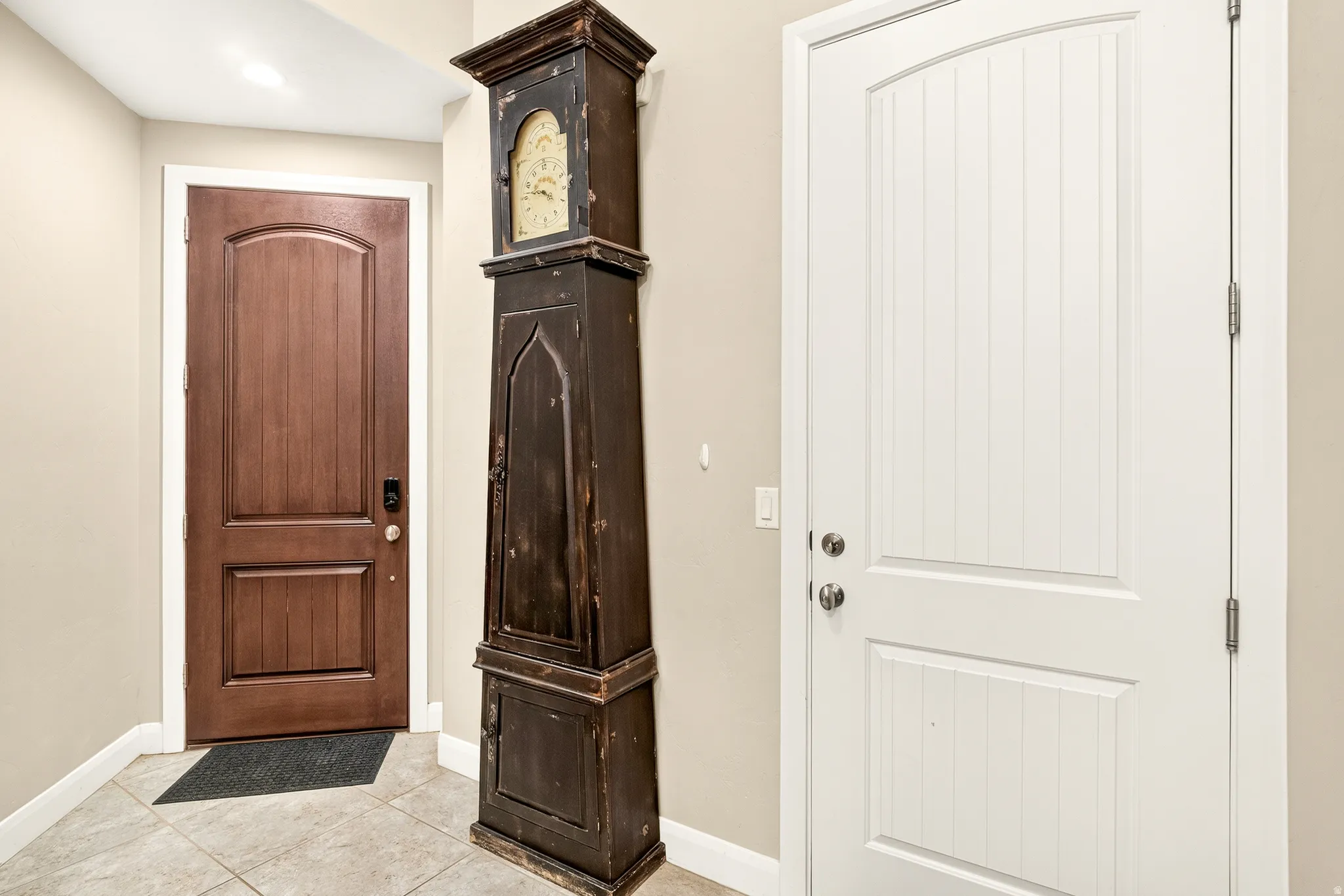 Tile flooring, white wall paint, brown paneled door, white paneled door, and white trim molding