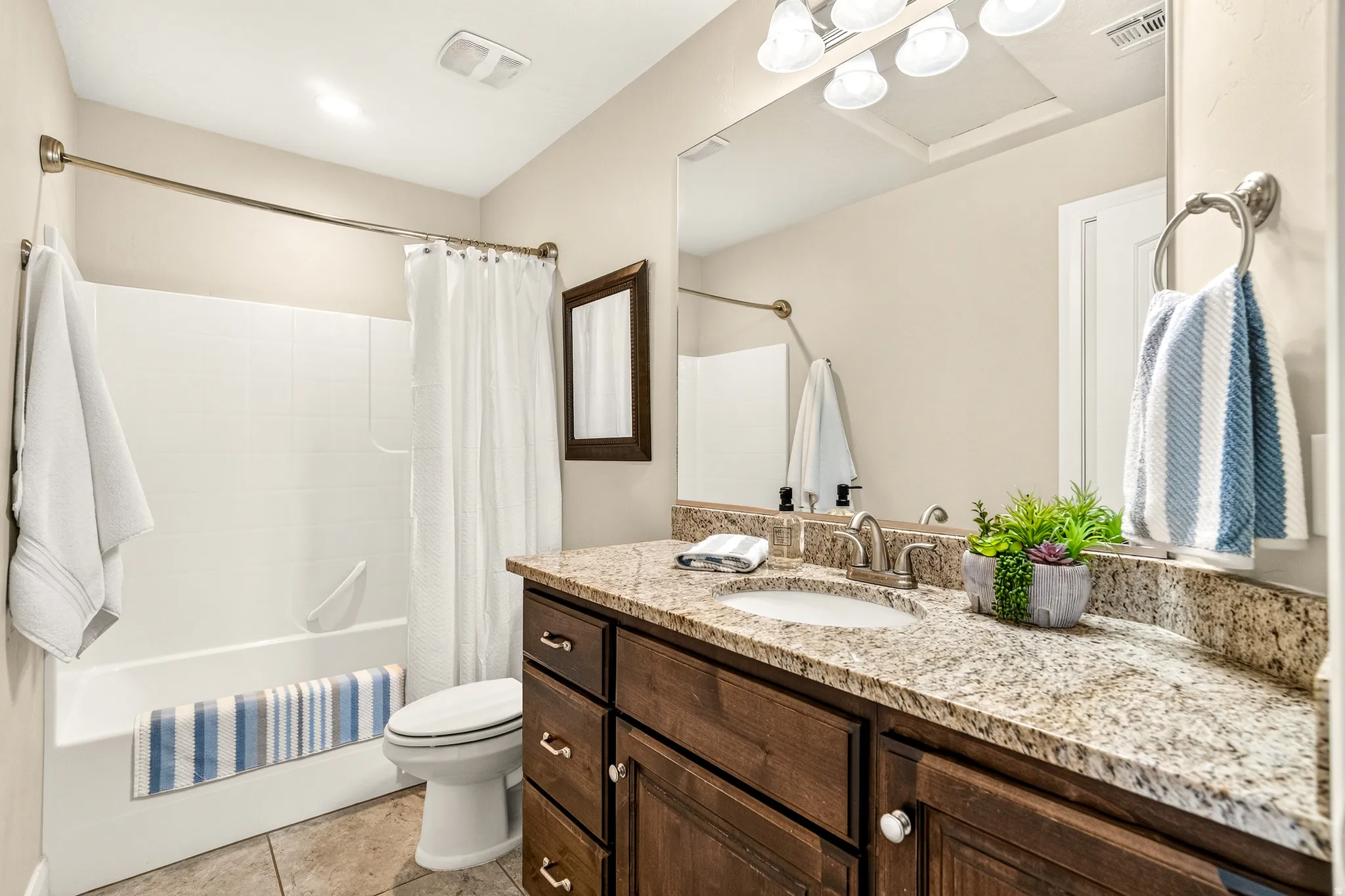 Wood-finish vanity with a single basin sink, brushed nickel faucet, and speckled stone countertop
