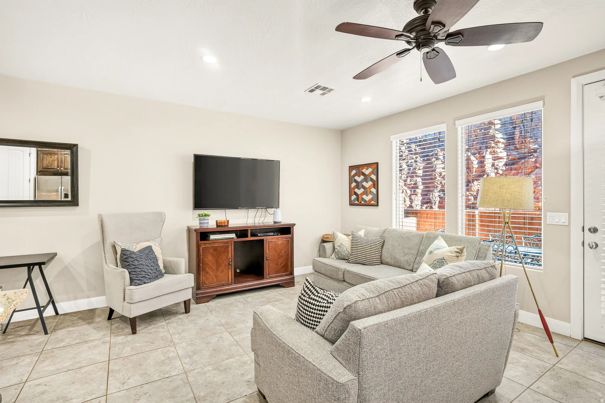 Spacious living area featuring tile flooring, ceiling fan, recessed lighting, and multiple windows