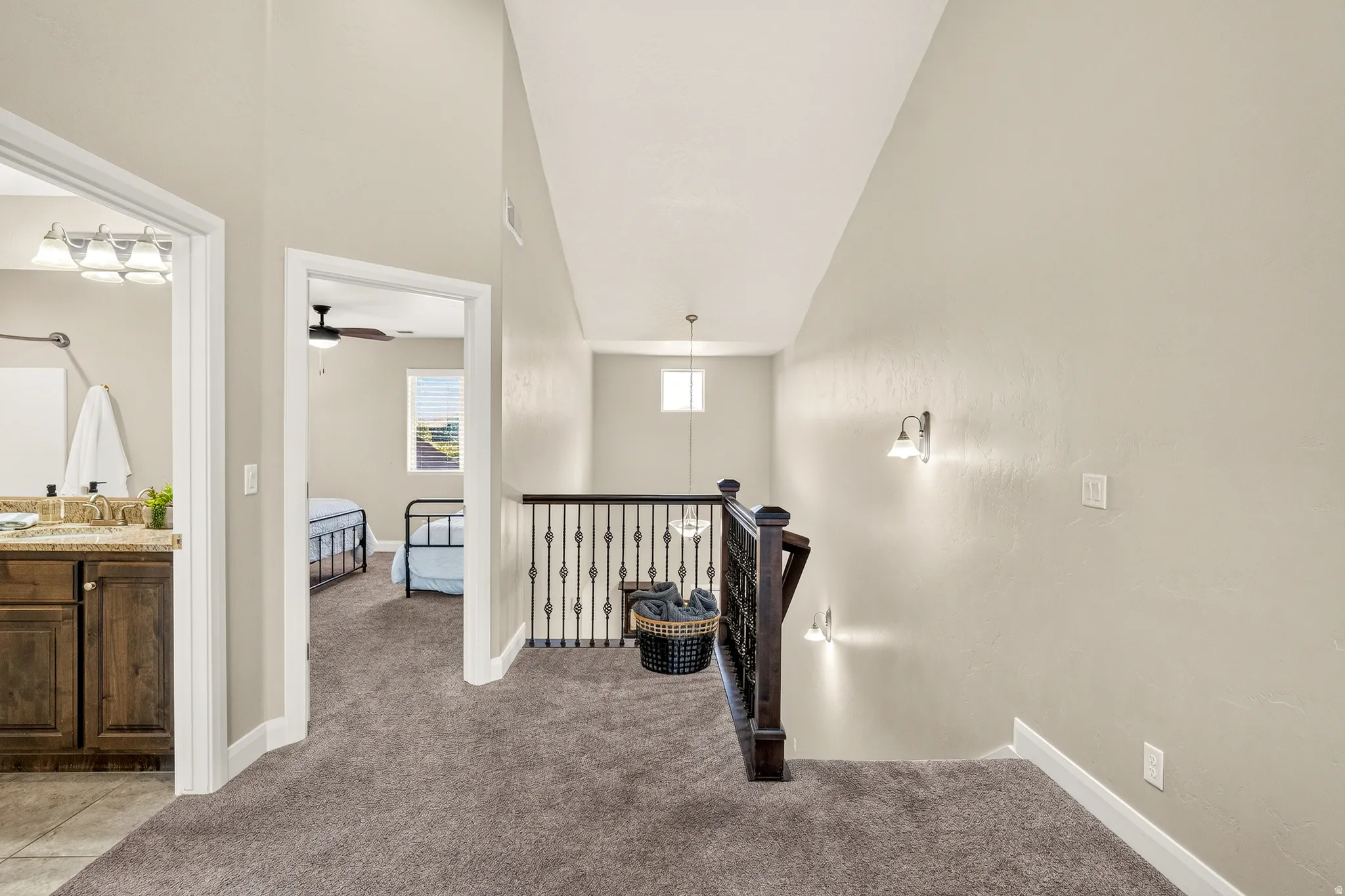 Carpeted landing with wrought iron and wood banister, recessed lighting, and wall sconces