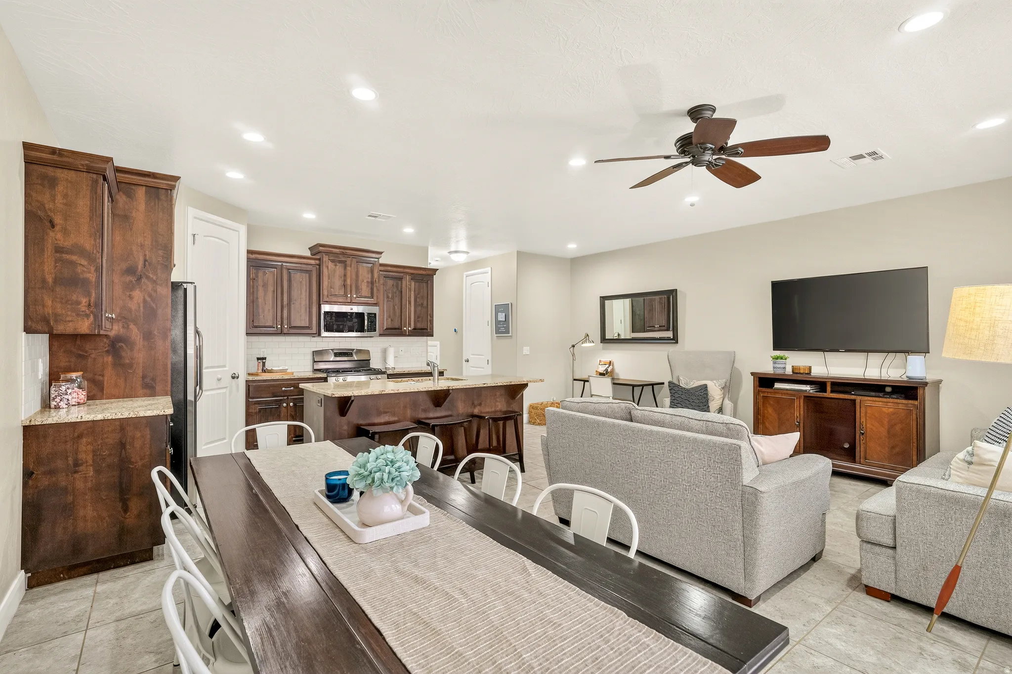 Recessed lighting, wood-finish cabinetry, stainless steel appliances, breakfast bar, and ceiling fan