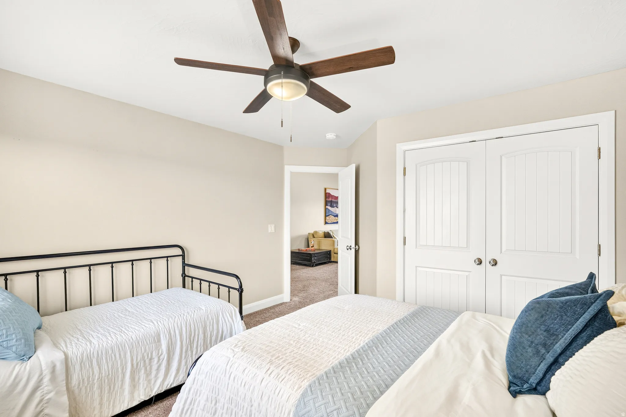 Ceiling fan with light fixture, neutral wall paint, carpet flooring, and white paneled bi-fold doors