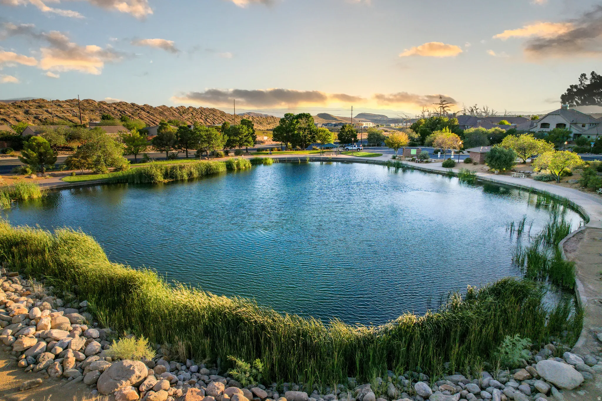 Community lake with walking path, surrounded by mature trees and natural landscaping