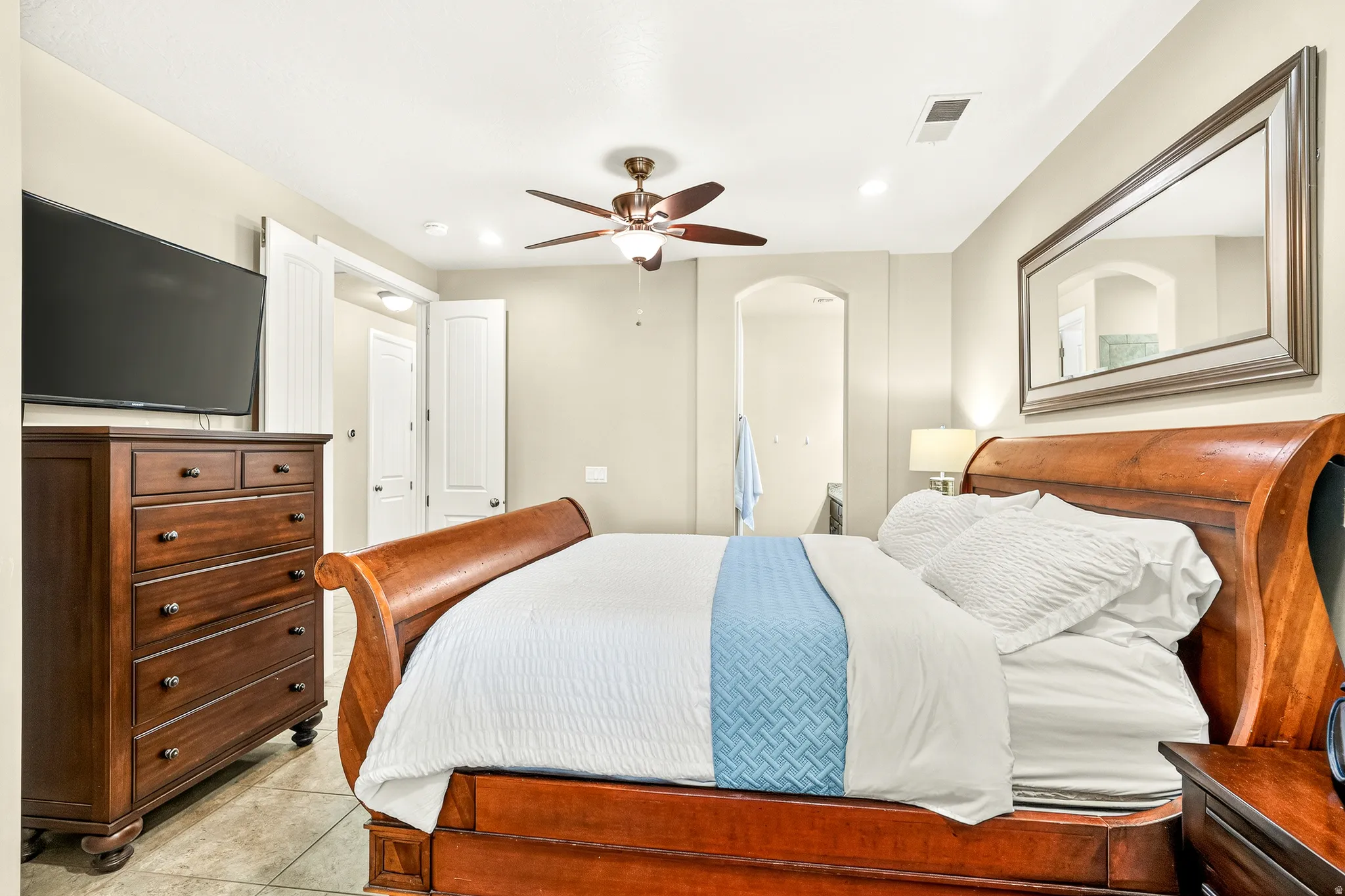 Recessed lighting illuminates the space, featuring a ceiling fan, arched doorway, and white paneled doors