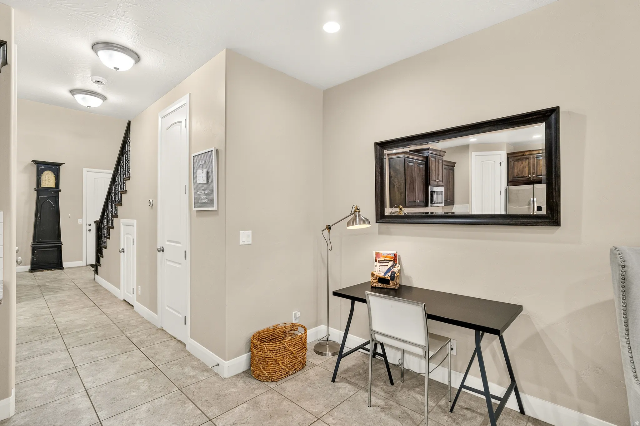 Tiled flooring throughout, staircase with dark wrought iron railing, recessed lighting, and neutral wall tones