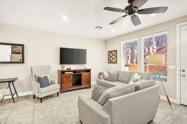 Spacious living area featuring tile flooring, ceiling fan, recessed lighting, and multiple windows