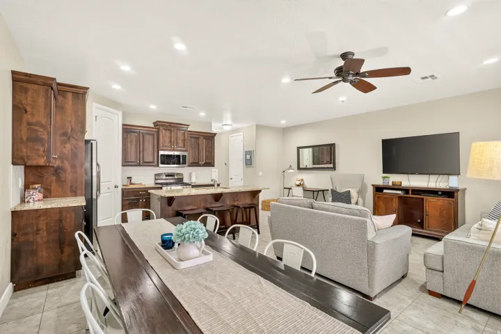 Recessed lighting, wood-finish cabinetry, stainless steel appliances, breakfast bar, and ceiling fan