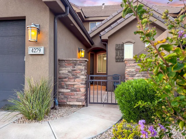 Stucco exterior with stone veneer accents, concrete pathway, and wrought iron gate