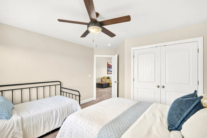 Ceiling fan with light fixture, neutral wall paint, carpet flooring, and white paneled bi-fold doors