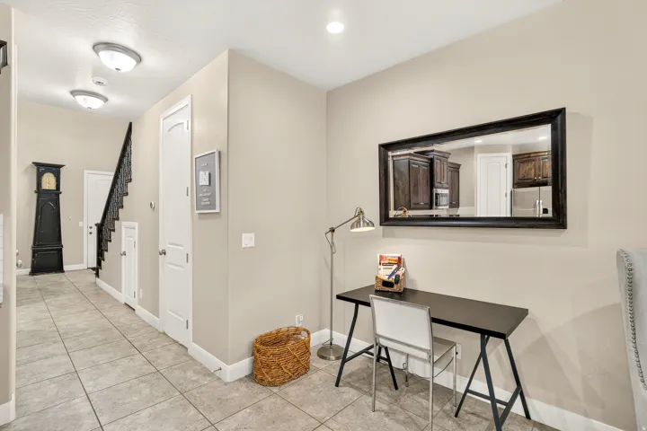 Tiled flooring throughout, staircase with dark wrought iron railing, recessed lighting, and neutral wall tones