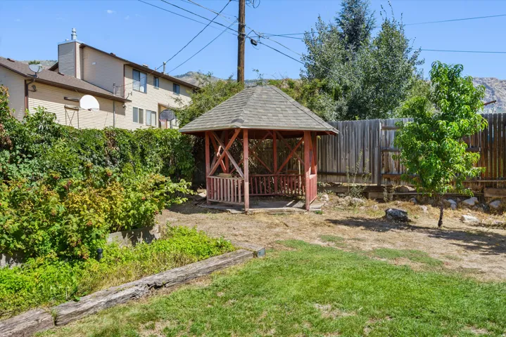 Backyard featuring a gazebo with a shingle roof, wood privacy fencing, and a manicured lawn area