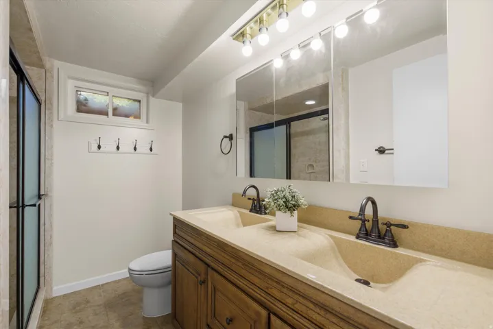 Dual vanity with integrated sinks, oil-rubbed bronze fixtures, and a wood-finish cabinet