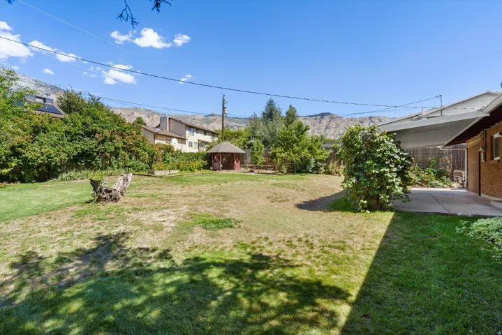 Expansive backyard featuring a covered patio, a wooden gazebo, and mature perimeter landscaping