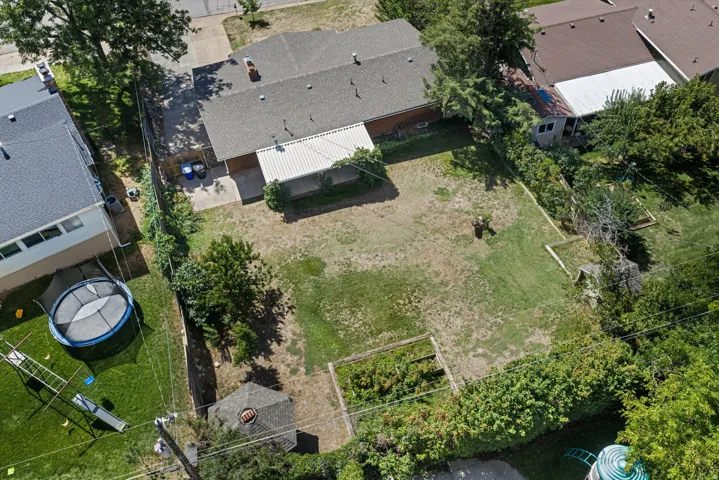 Expansive backyard with a covered patio, established plantings, and a detached shed