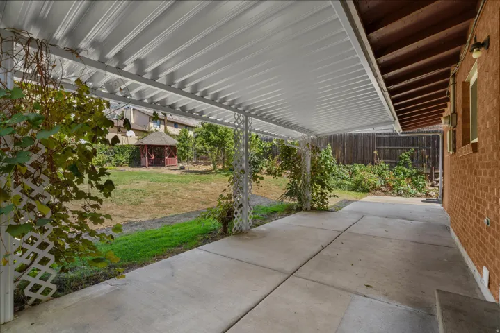 Covered patio with a concrete slab, brick exterior, and a detached gazebo