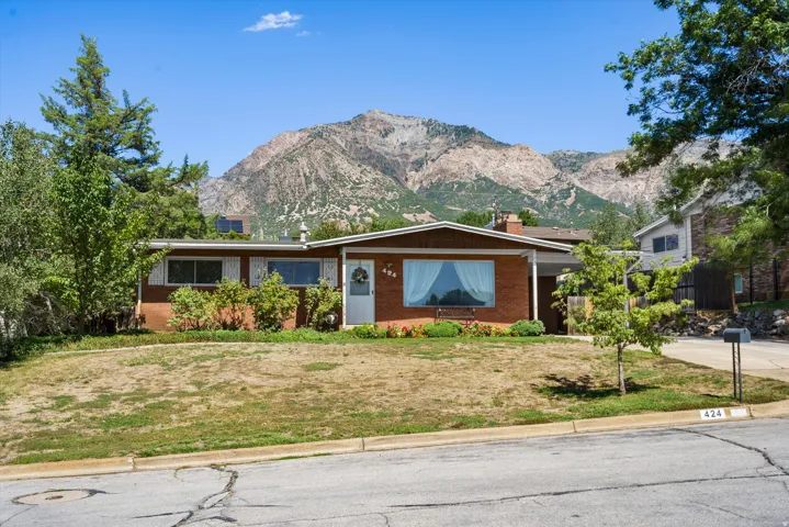Brick ranch-style home featuring a covered entryway and a prominent mountain backdrop