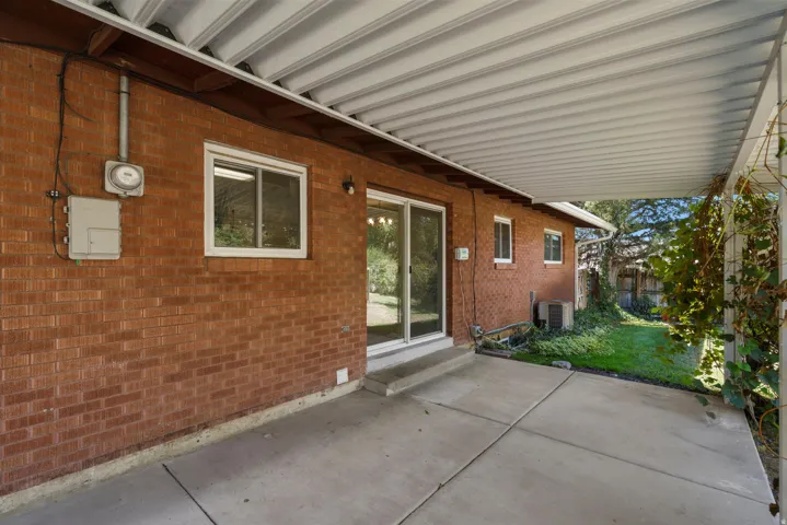 Covered patio with a concrete surface, a brick exterior, and a sliding glass door