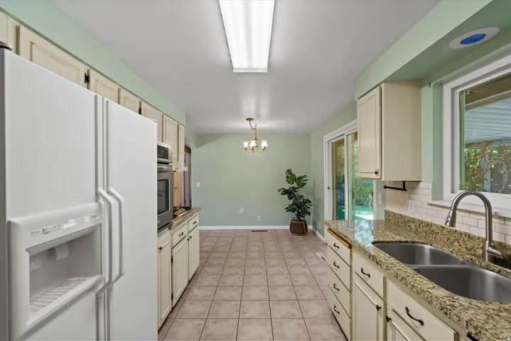 Kitchen featuring tile flooring, white cabinetry, granite countertops, and a double basin stainless steel sink