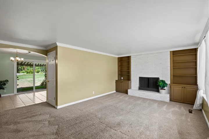 Living area featuring a brick fireplace surround, built-in shelving, and carpet flooring