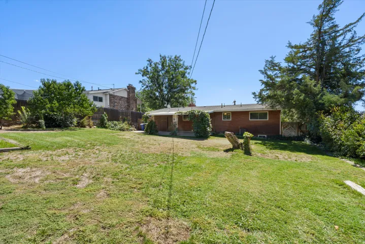 Expansive grassy yard with mature trees and a brick-sided structure