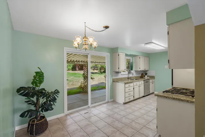 Kitchen featuring white cabinetry, light-colored granite countertops, tile flooring, and stainless steel appliances