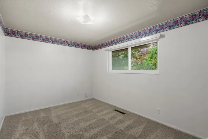 Neutral wall finishes with a window, ceiling light fixture, and carpeted flooring