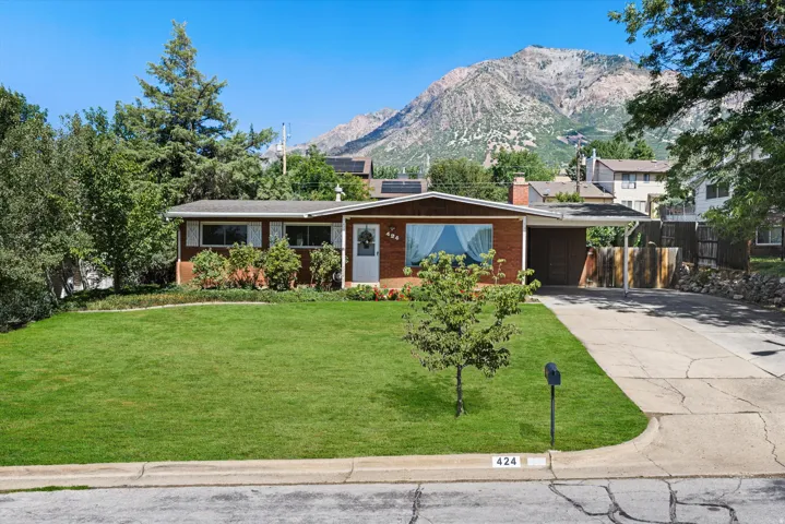 Brick exterior with a prominent front lawn, an attached carport, and a paved driveway