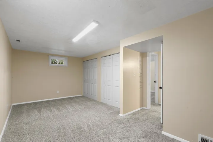 Carpeted flooring, neutral wall tones, multiple bi-fold closet doors, and recessed window