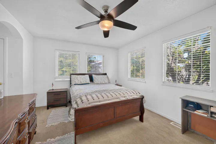 Recessed lighting, ceiling fan with integrated light, multiple windows with blinds, and neutral carpeting