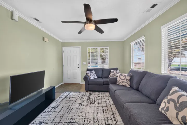 Recessed lighting, crown molding, ceiling fan, multiple windows with blinds, and wood-finish flooring