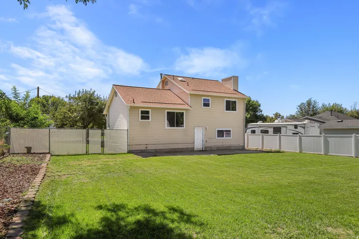 Expansive backyard featuring a manicured lawn, established landscaping, and a combination of privacy fencing and chain-link fencing