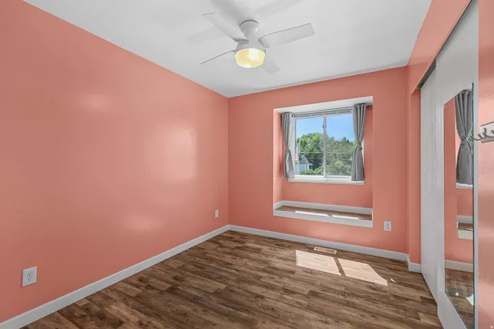 Wood-finish flooring, ceiling fan, window with sill, and mirrored closet doors