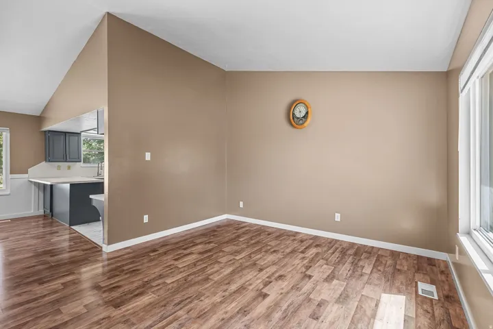 Vaulted ceiling, wood-finish flooring, large window, kitchen pass-through, dark cabinetry