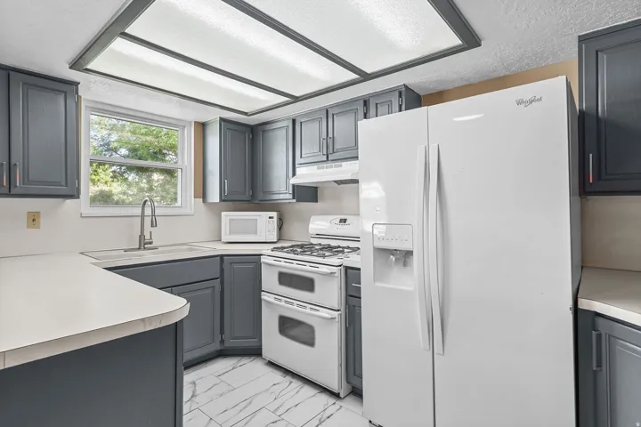 Kitchen featuring gray cabinetry, white countertops, built-in double oven, full-size refrigerator, and window above the sink