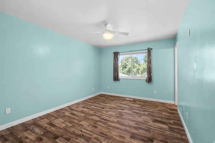Wood-finish flooring, white ceiling, white ceiling fan, and a window with a white frame