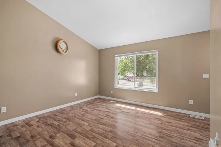 Vaulted ceiling, wood-finish flooring, and a large window
