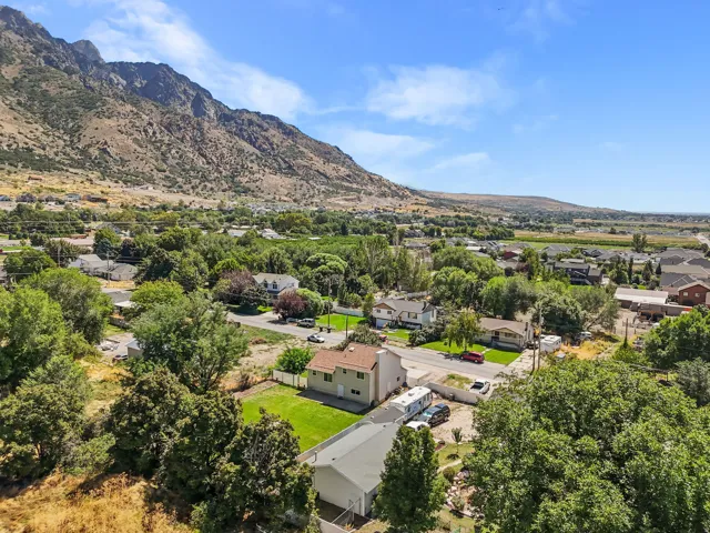 Mountain backdrop, residential neighborhood, green landscaping, asphalt roadway, clear blue sky