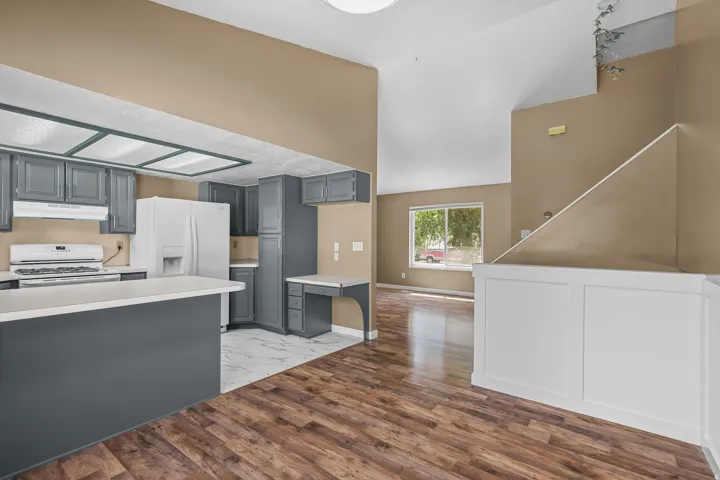 Kitchen featuring gray cabinetry, white appliances, and a built-in desk area