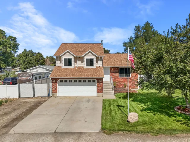 Exterior featuring brick and siding finishes, a two-car garage, dormer windows, a manicured lawn, and a concrete driveway