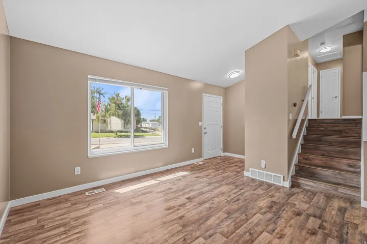 Wood-finish flooring, white trim, recessed lighting, white panel doors, and a wood staircase with white risers
