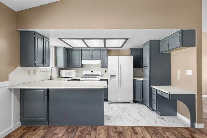 Kitchen featuring dark gray cabinetry, white countertops, built-in desk, and white tile flooring
