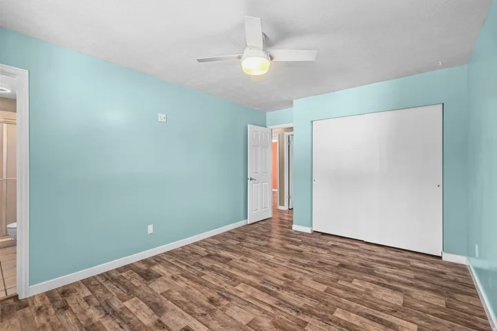 Wood-finish flooring, white ceiling fan with integrated lighting, and white bi-fold closet doors
