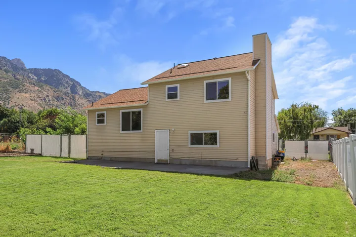 Expansive yard featuring a green lawn, mountain backdrop, and composite fencing