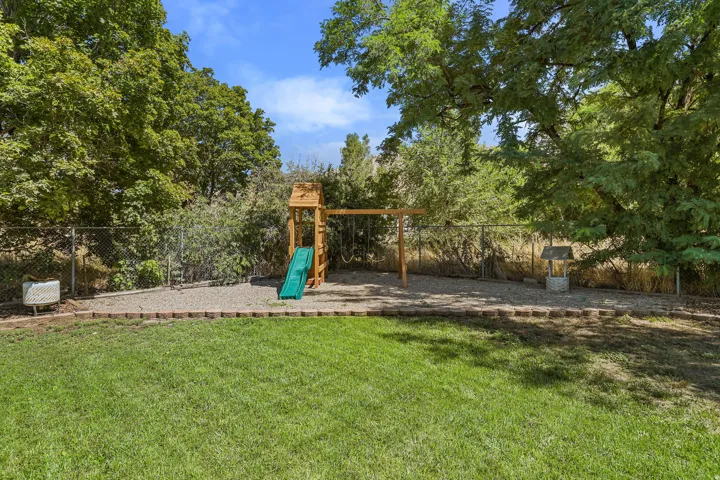 Expansive yard featuring a manicured lawn, chain-link fencing, and mature trees