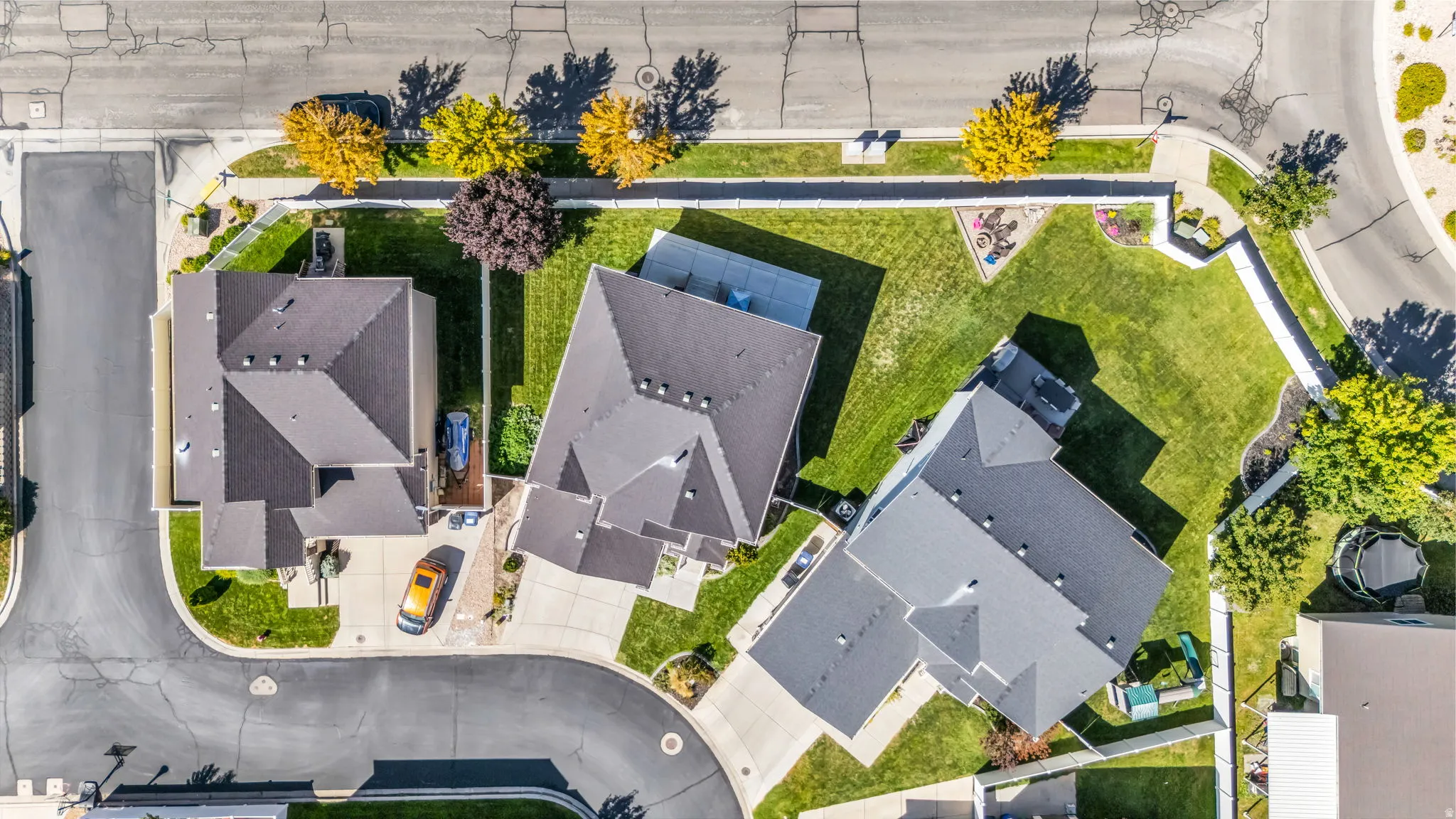 Aerial perspective showcasing multiple properties, street access, and established landscaping