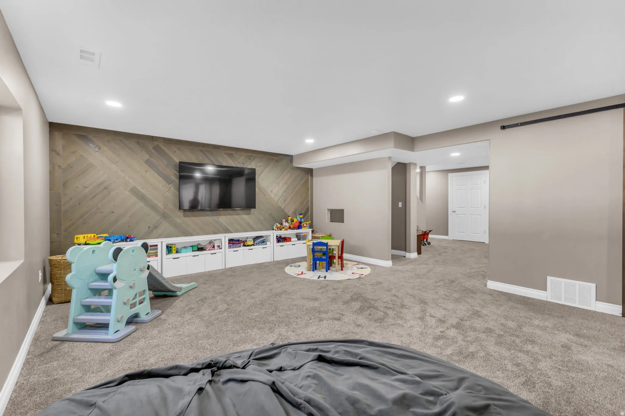 Recessed lighting, wood-finish accent wall, built-in lower cabinetry, and plush carpet flooring