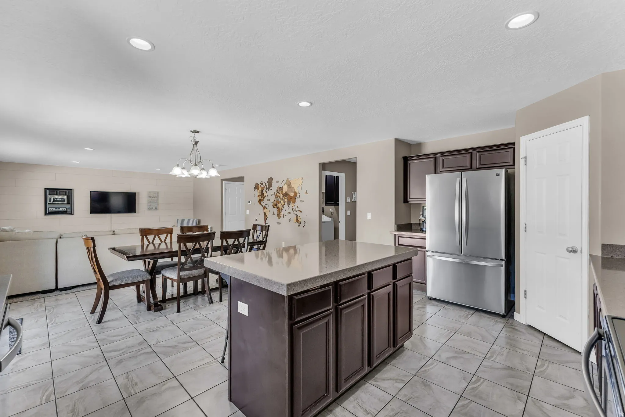 Kitchen featuring a central island with stone countertop, stainless steel refrigerator, dark wood-finish cabinetry, and tile flooring