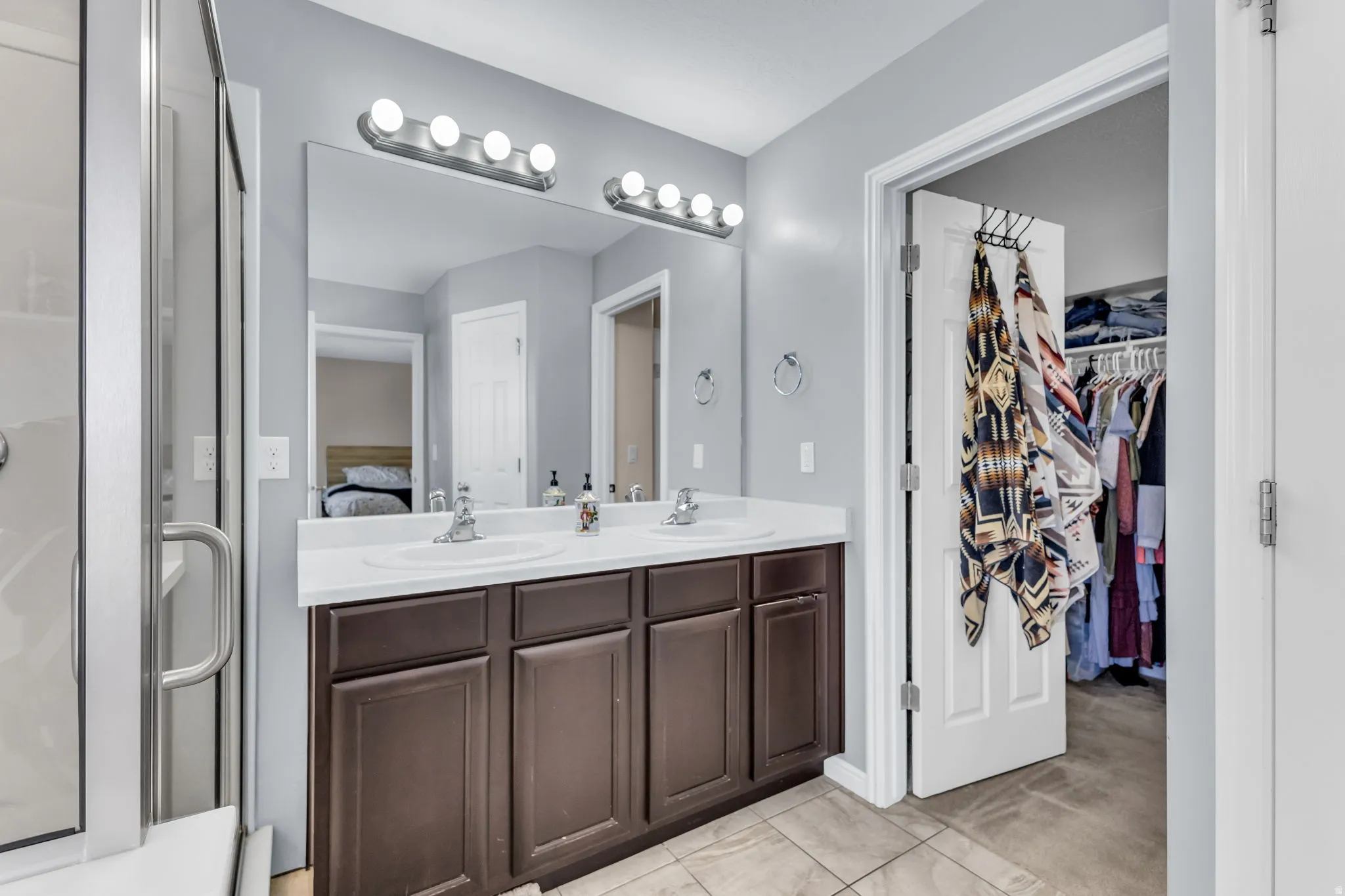 Double vanity with white countertop, brown cabinetry, and chrome fixtures